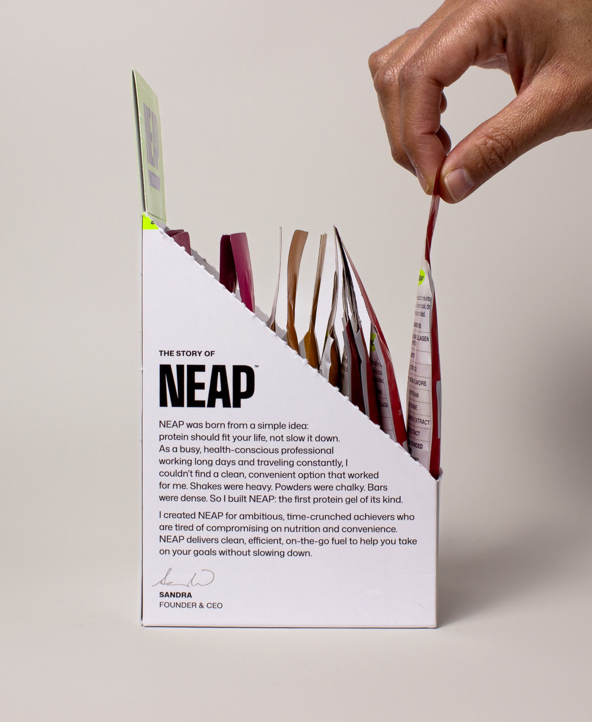 Side view of hand grabbing a NEAP Original collagen protein gel packet out of NEAP Original Variety Box display box.